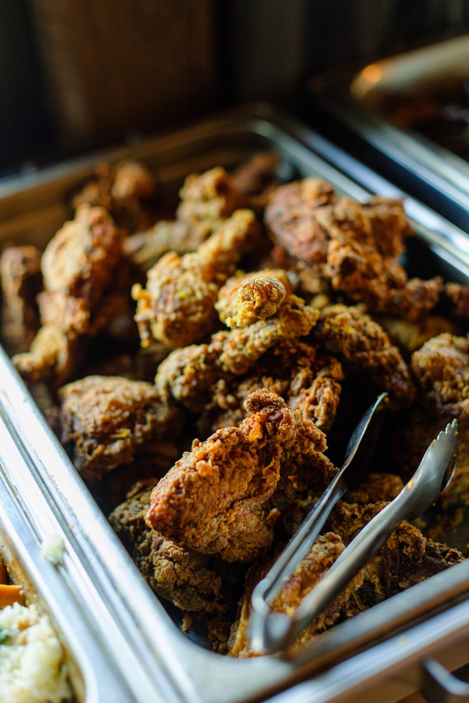 Close-up of golden brown fried chicken pieces displayed in a catering tray.