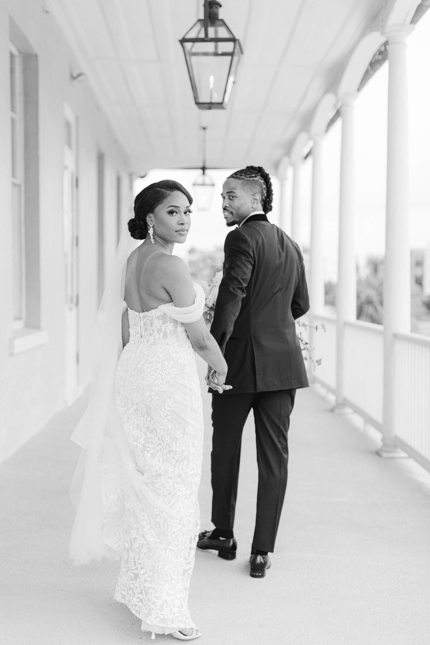 A romantic black and white wedding photo captured in an elegant columned hallway.
