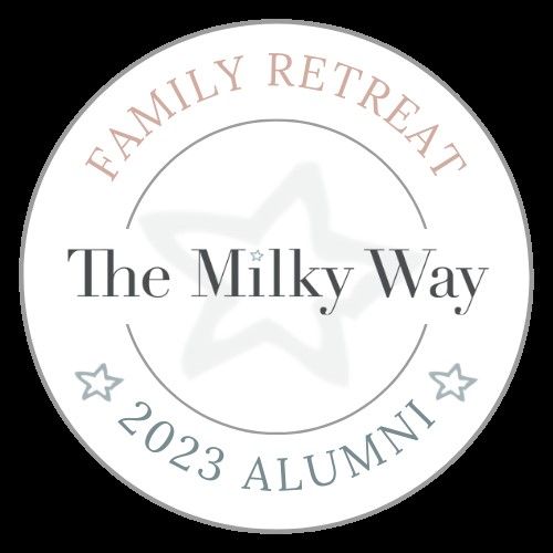 White circular logo for The Milky Way Family Retreat 2023 Alumni with decorative stars.