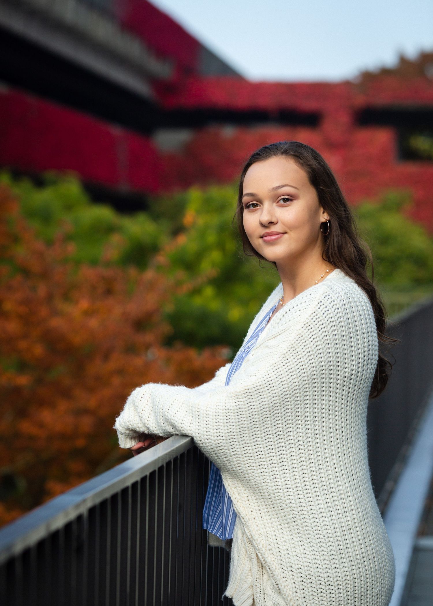 High school girl in an oversized sweater leaning against a railing