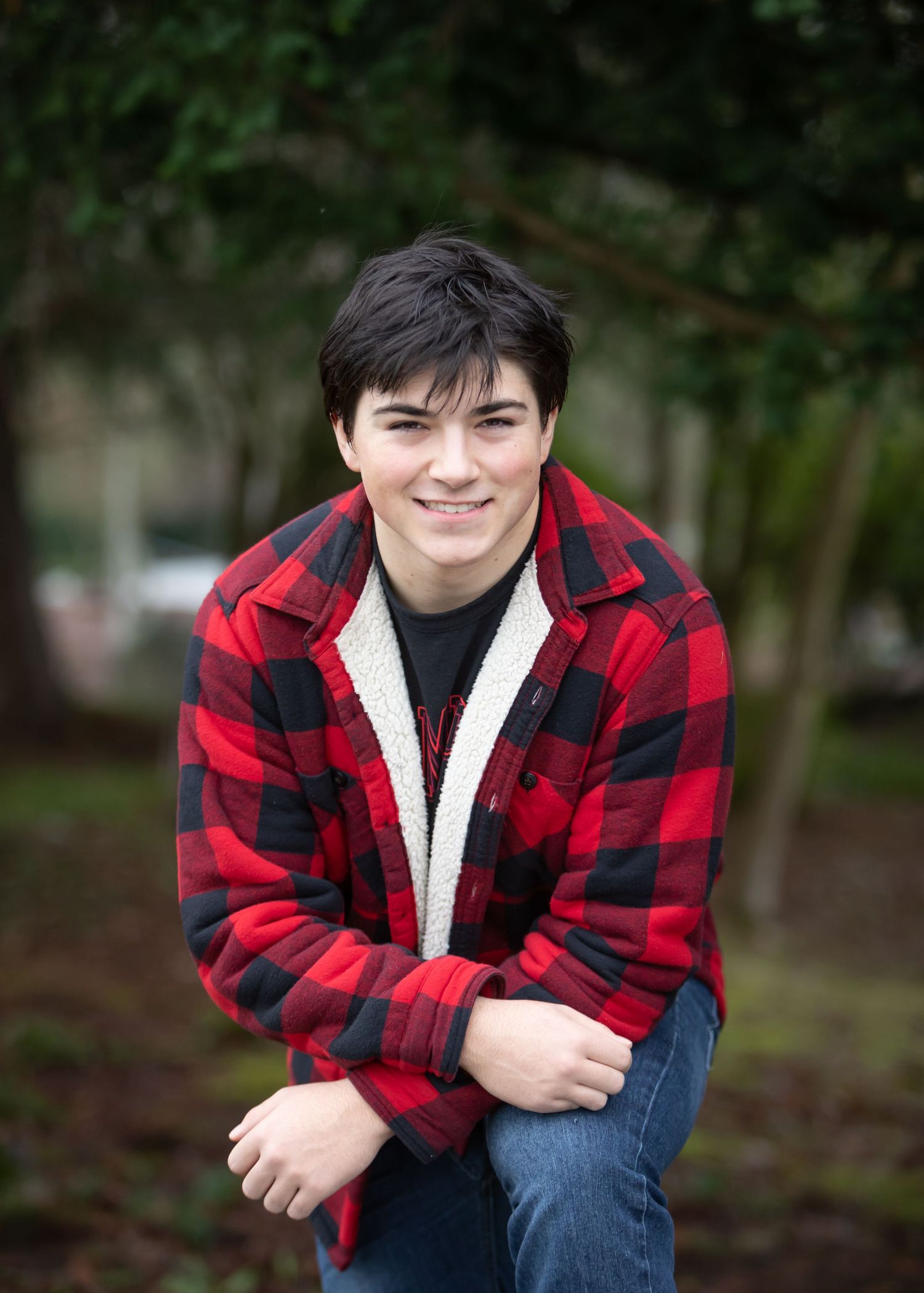 High school boy wearing flannel leaning on his knee