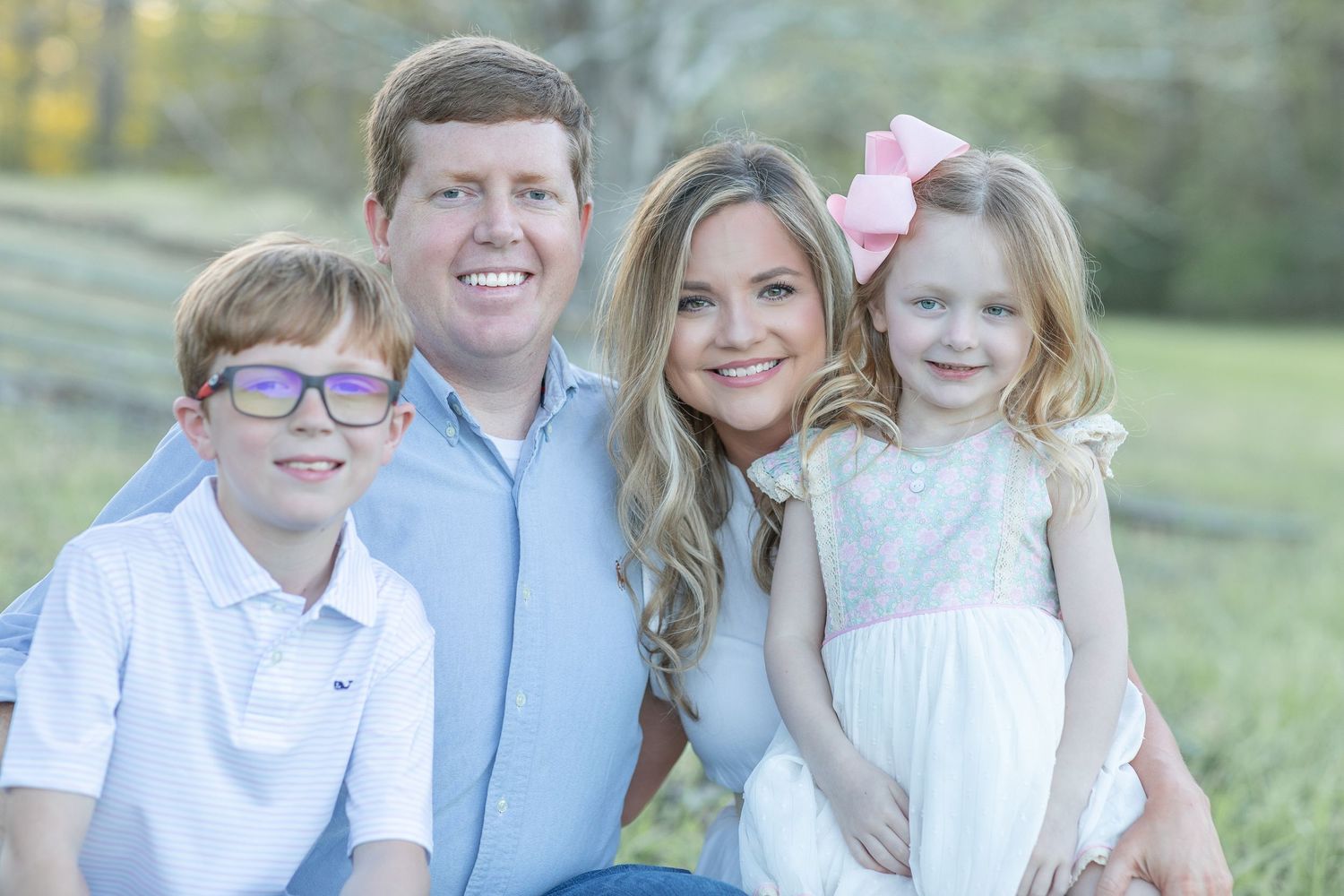 Family in coordinated blue and white outfits poses together outdoors.