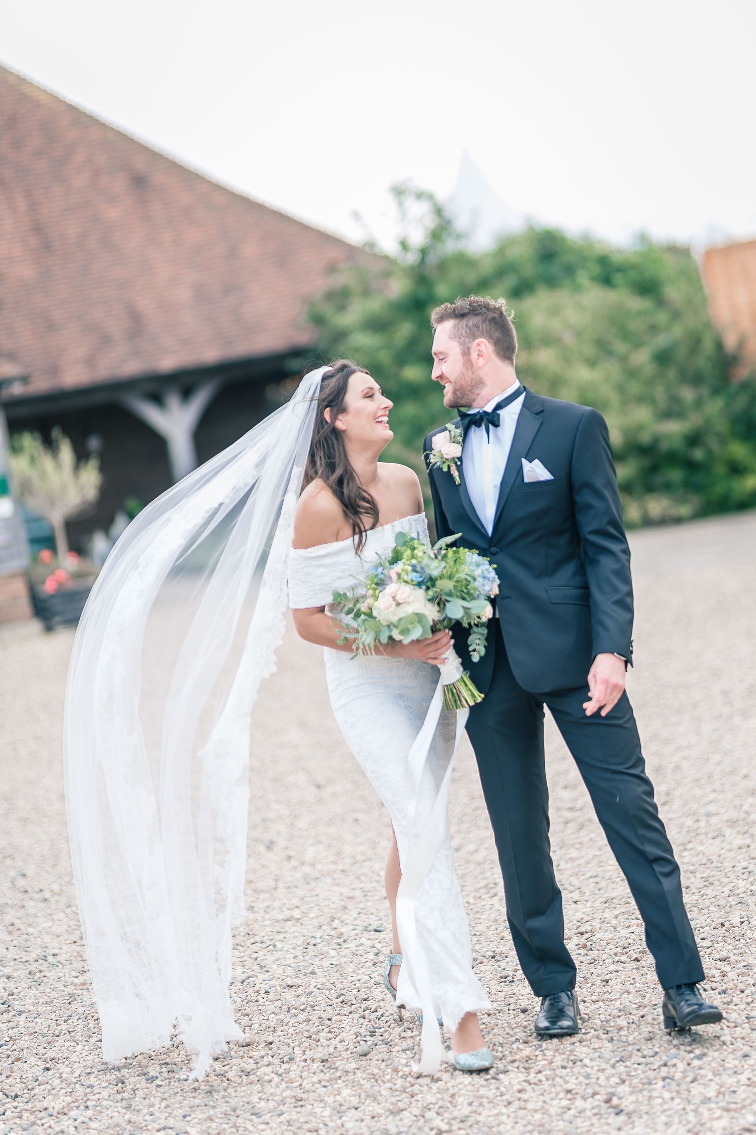 A couple shares a joyful moment on their wedding day on a rustic outdoor path.