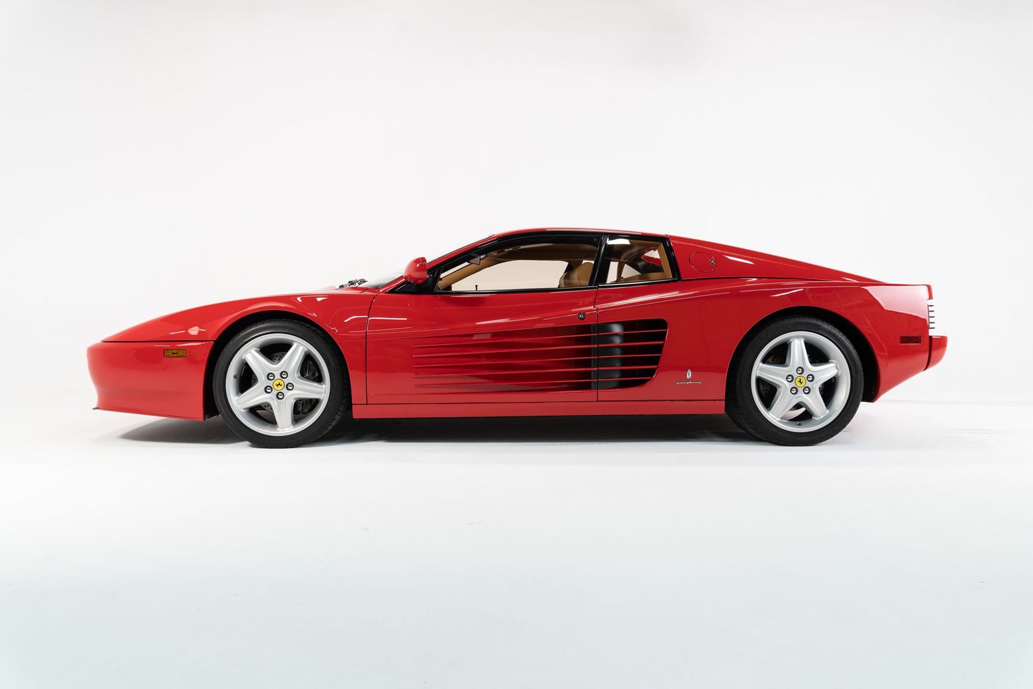 Side profile view of a sleek red Ferrari sports car against white background.