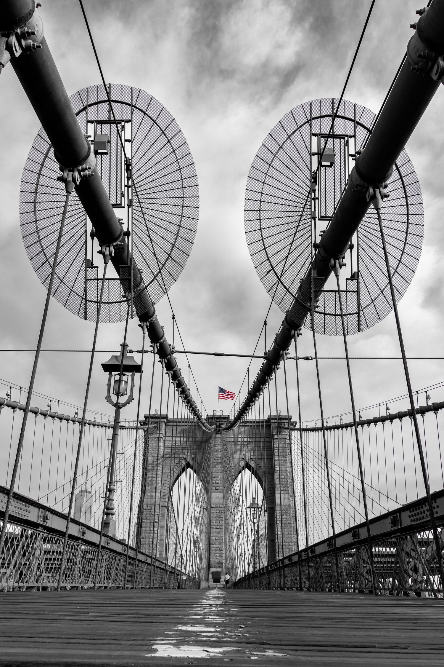 A lone jogger on Brooklyn Bridge looking towards Manhattan and One World Trade Center in black and white by Kush Rattan 