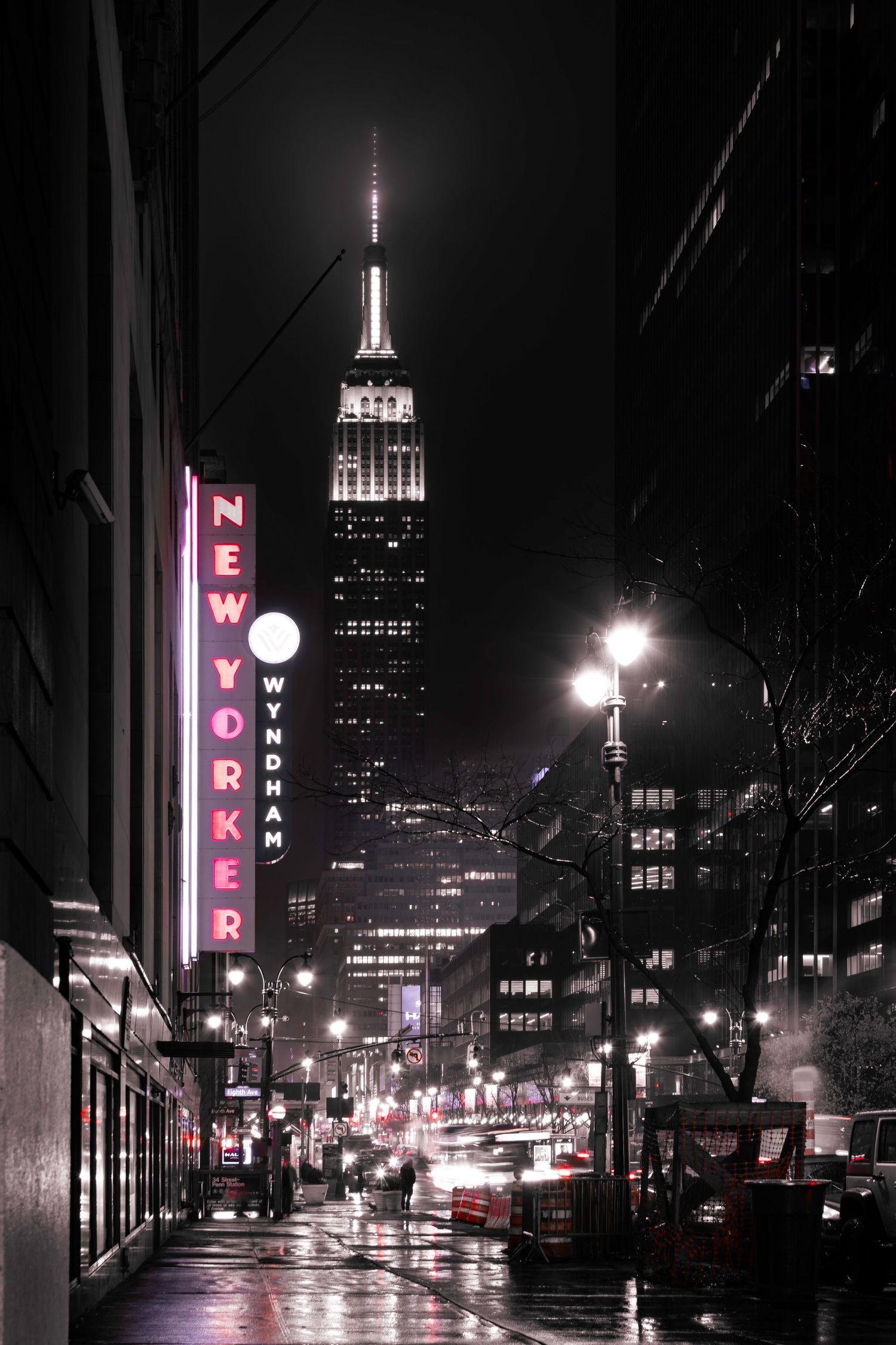 The Empire State Building and the New Yorker hotel by Eighth Avenue on a dark rainy night in New York Manhattan by Kush 