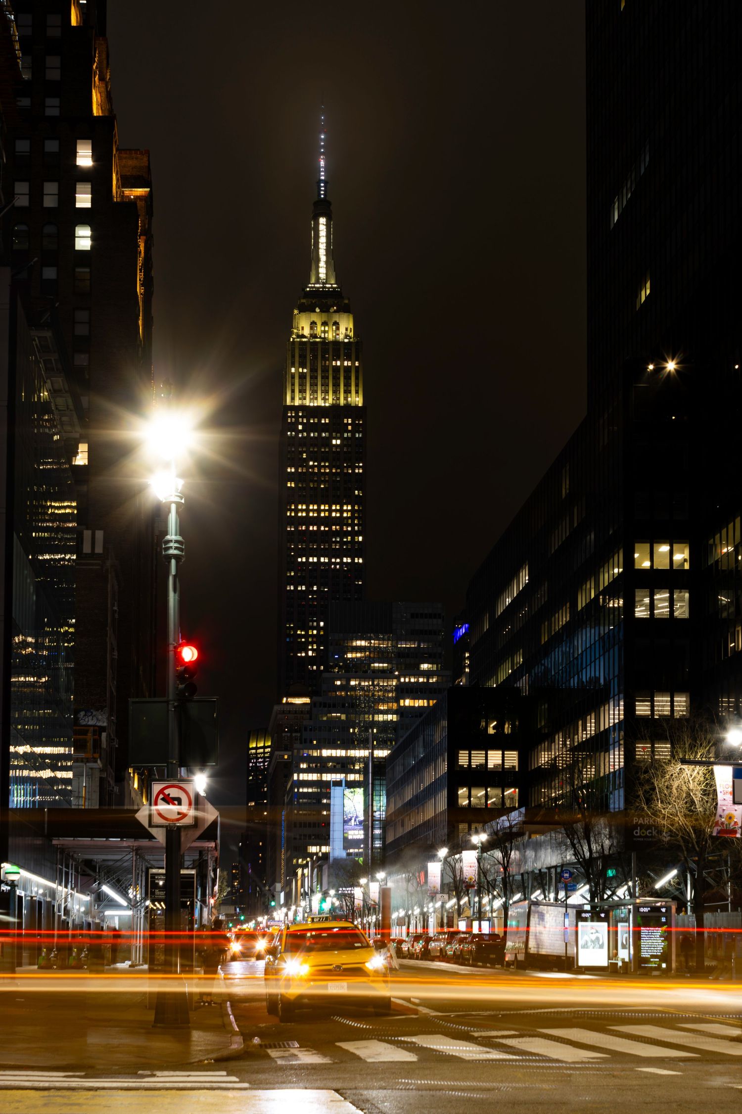 The Empire State Building at night with yellow taxi in Manhattan New York by Kush Rattan Photography