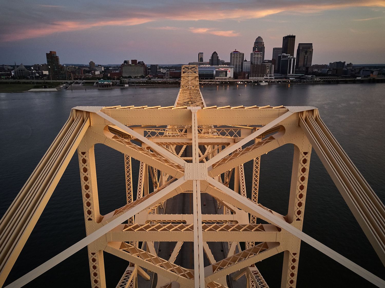 Panoramic sunset view of Baltimore harbor with golden bridge structure in foreground.