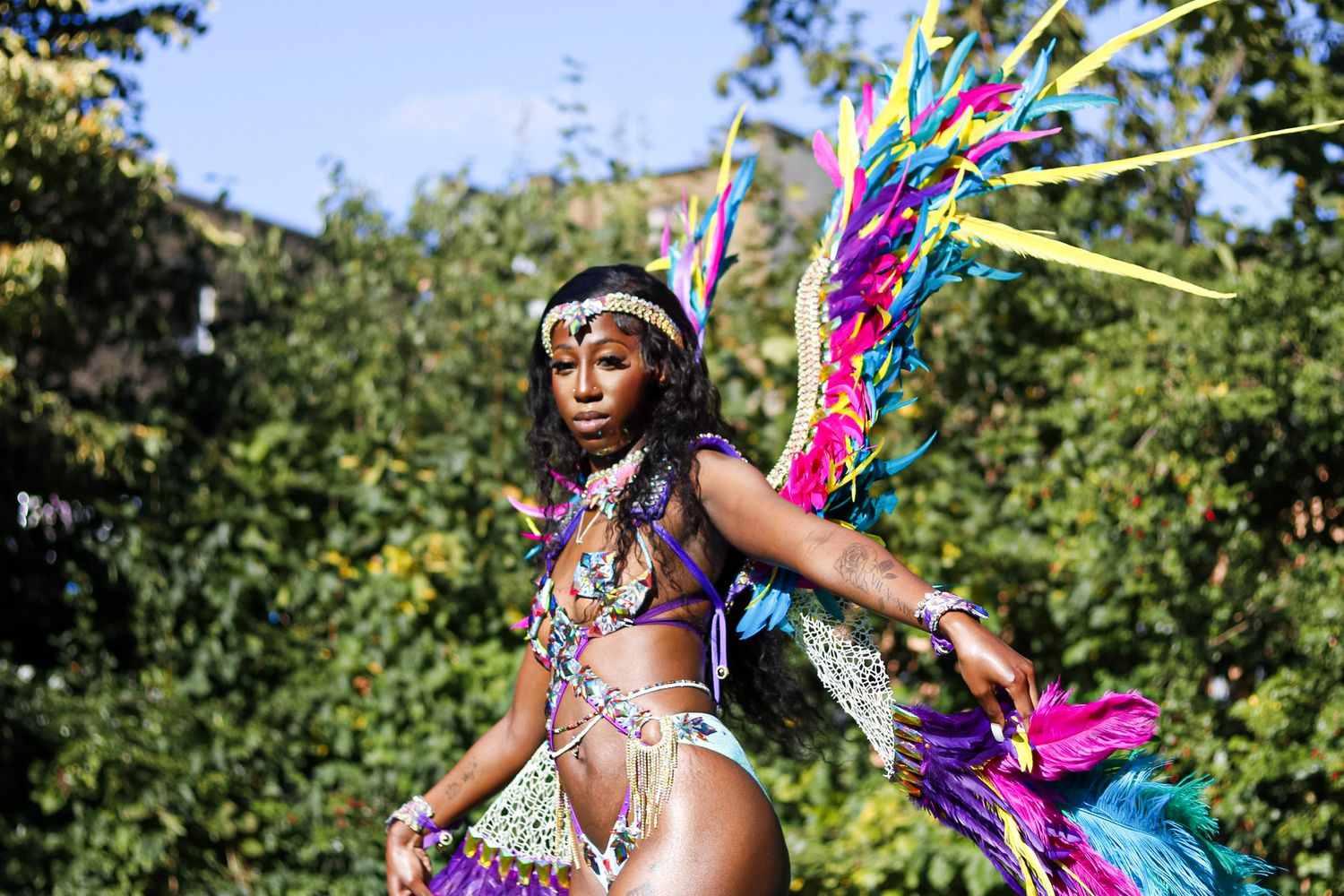 Vibrant carnival costume with colorful feathers and jeweled details captured in outdoor setting.