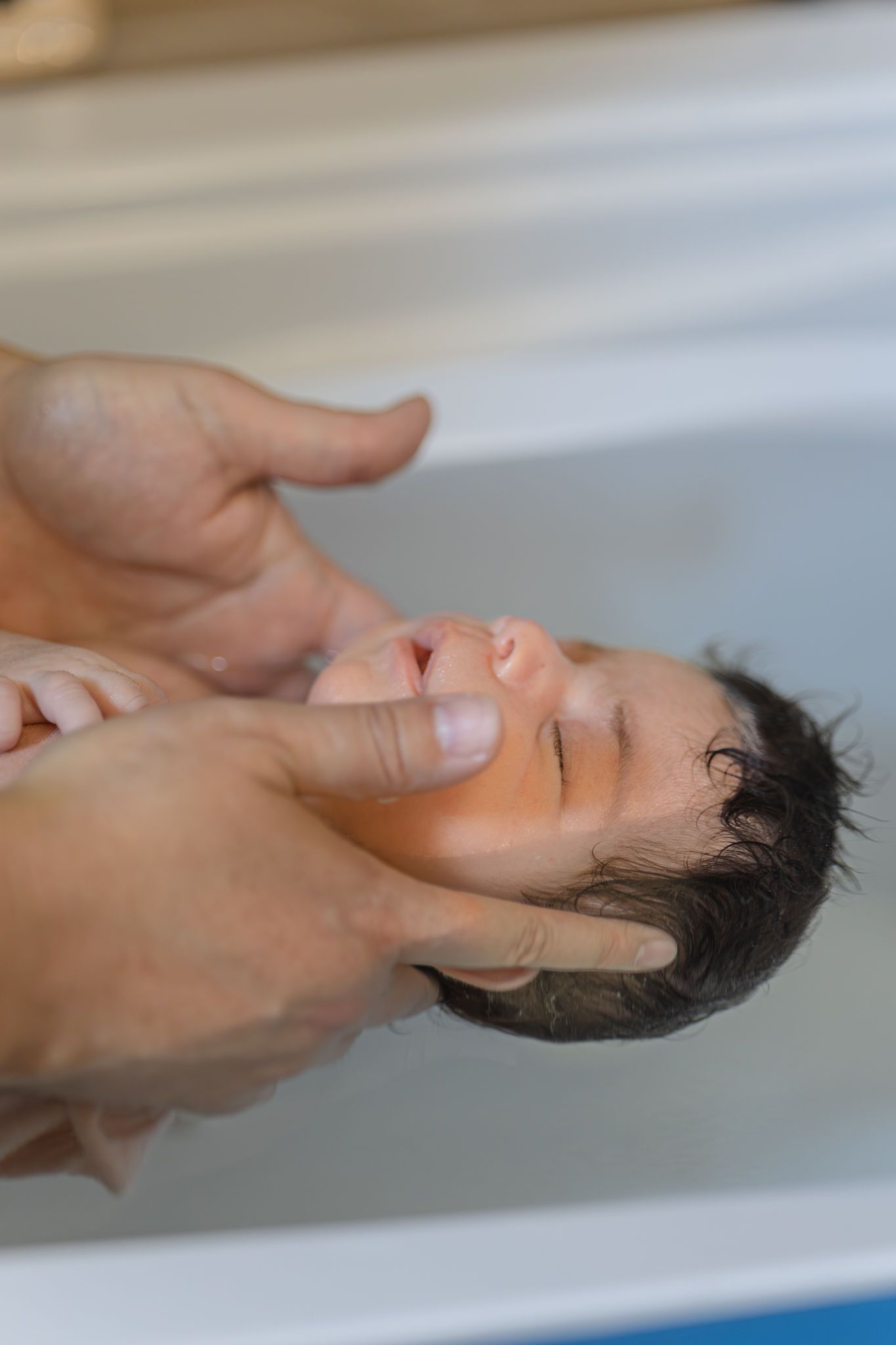 Un nouveau-né détendu presque totalement submergé dans l'eau de son bain thalasso.