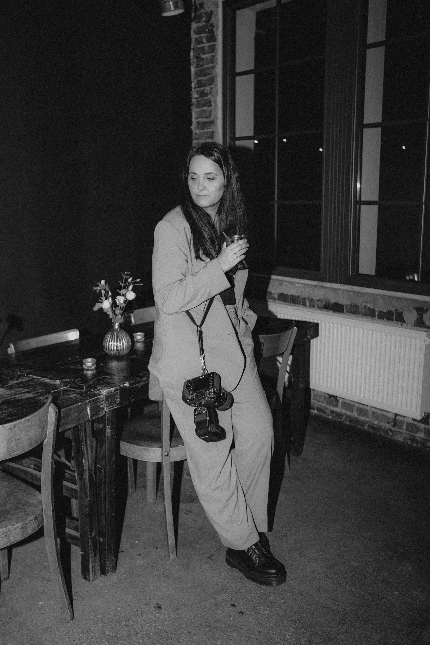 Stylish woman holding camera in elegant black and white restaurant setting.
