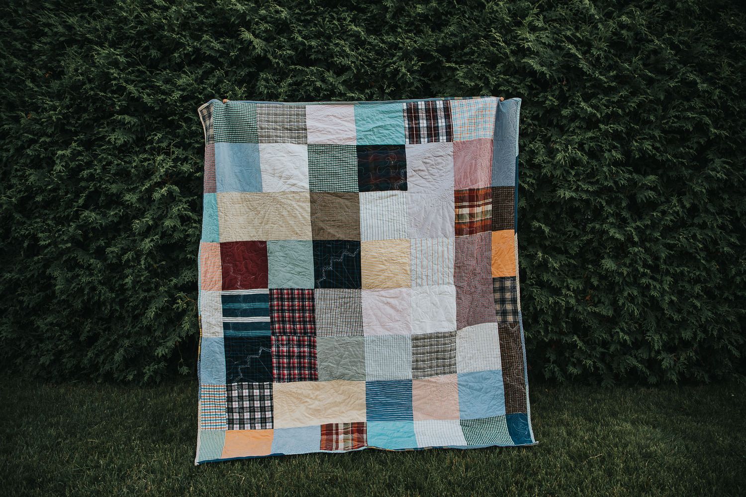 Back side of a double sided memory quilt featuring a square patchwork of dress shirts.