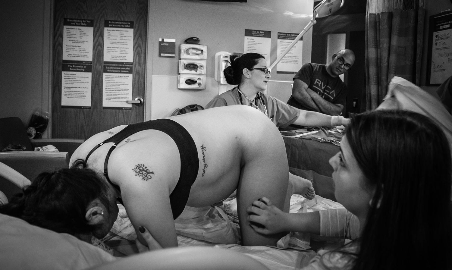Pregnant Woman On Hands And Knees Birthing Baby As Father Looks On