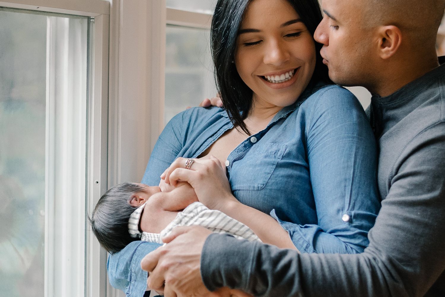 Woman Breastfeeding Baby While Smiling At Her Partner
