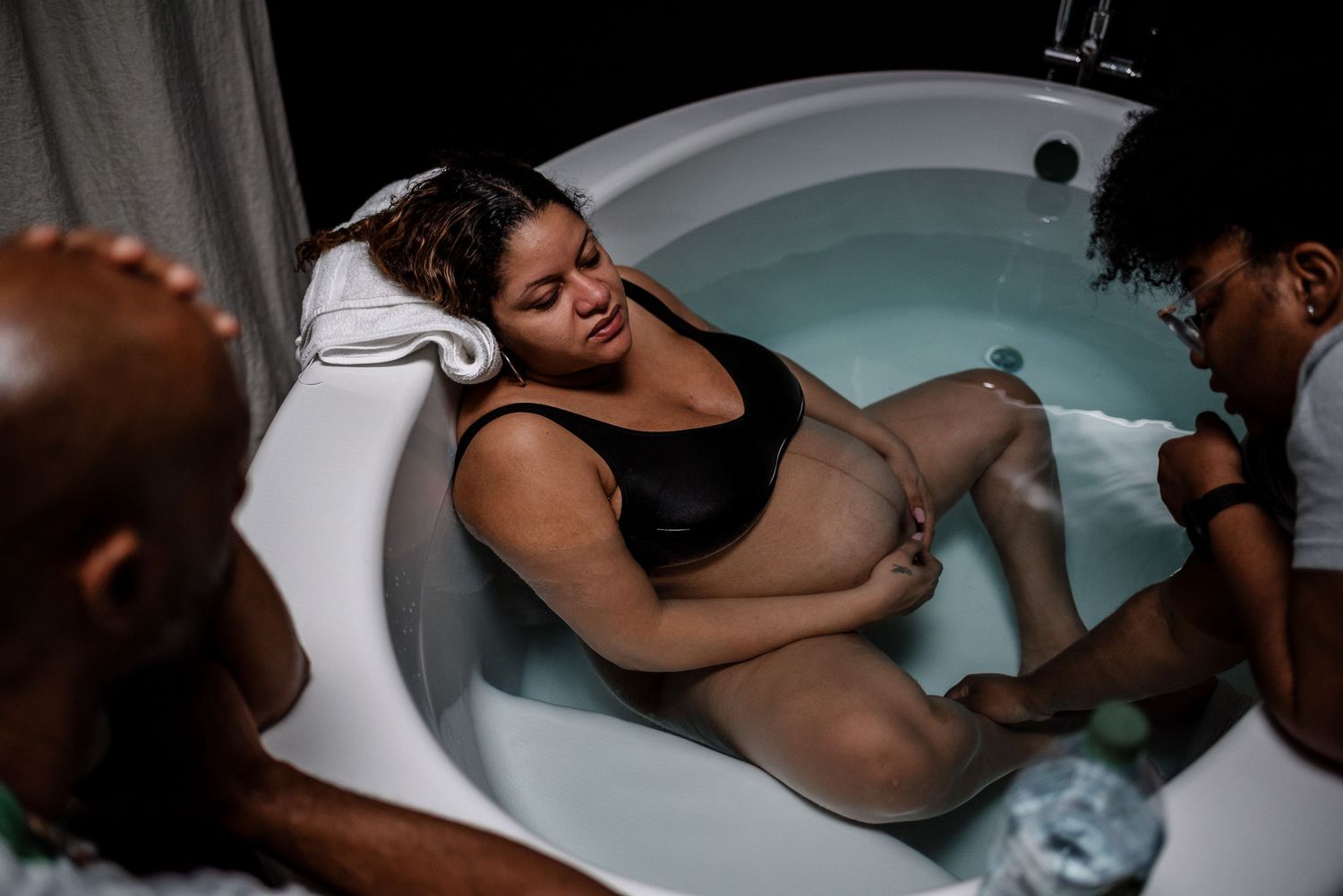 Woman With Eyes Closed Laboring In Birth Tub With Doula Performing Acupressure
