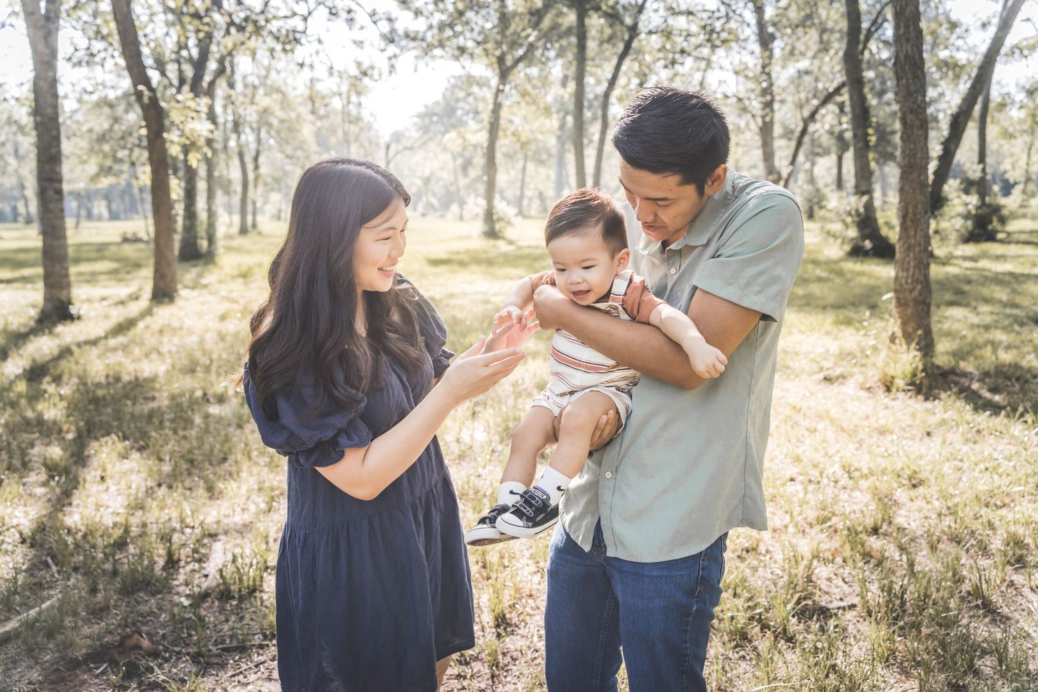 A romantic outdoor photo session in a sun-dappled forest with warm natural lighting and soft bokeh effects.  Pearland Family Photographer