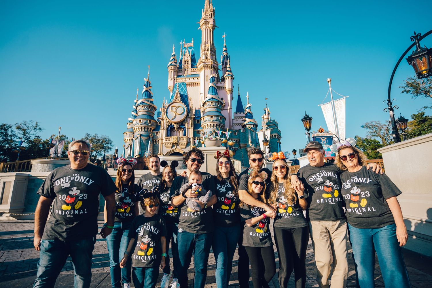 Friends in coordinated dark t-shirts gather for a photo at Disney's Magic Kingdom castle.