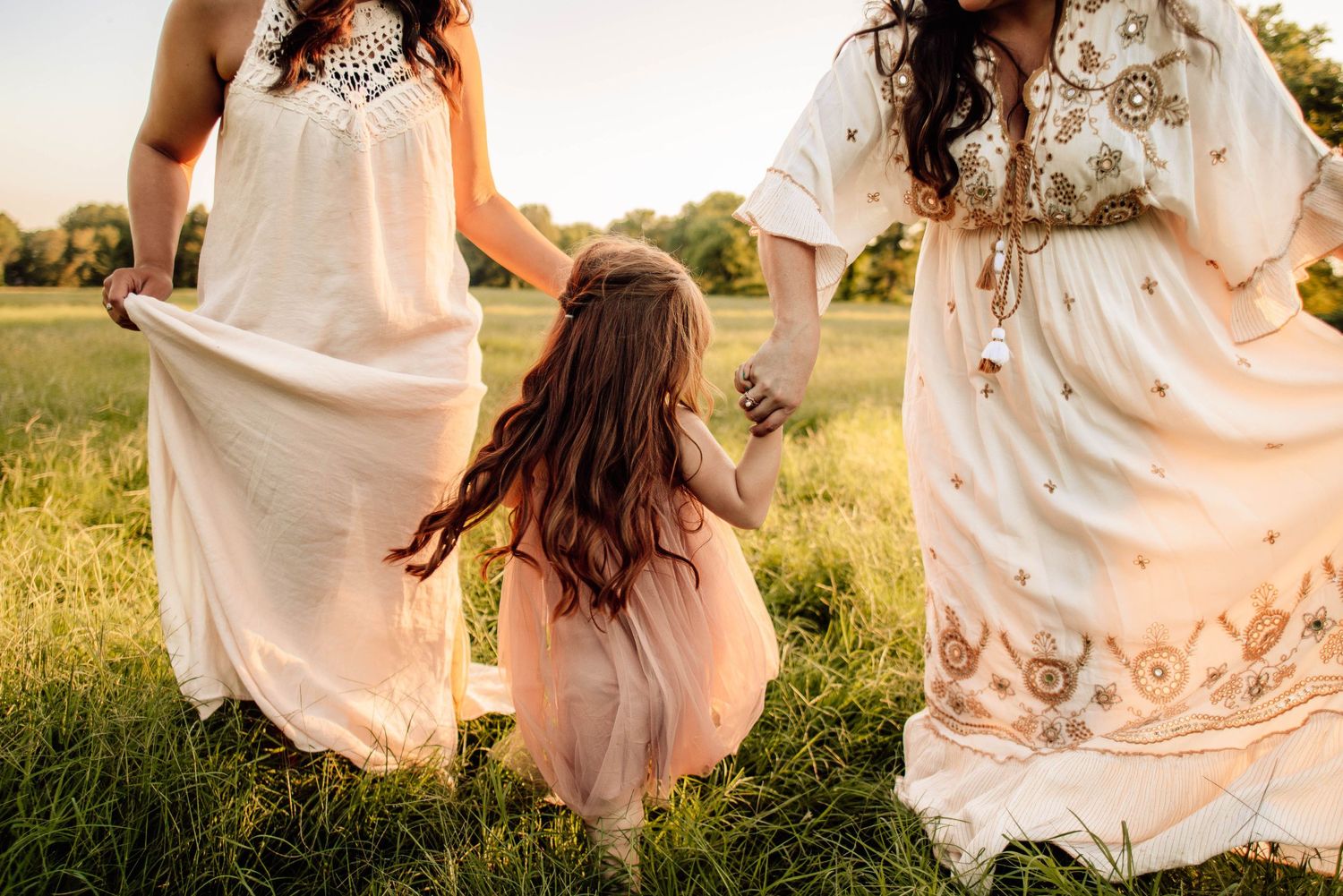 Person in flowing white dress twirls in a sunlit meadow.
