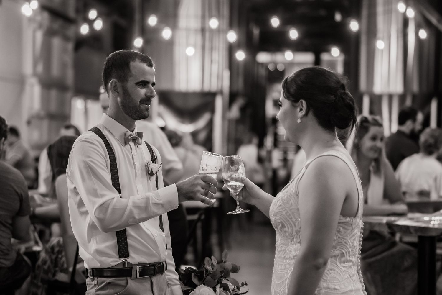 A couple shares a toast with champagne glasses during their wedding reception.