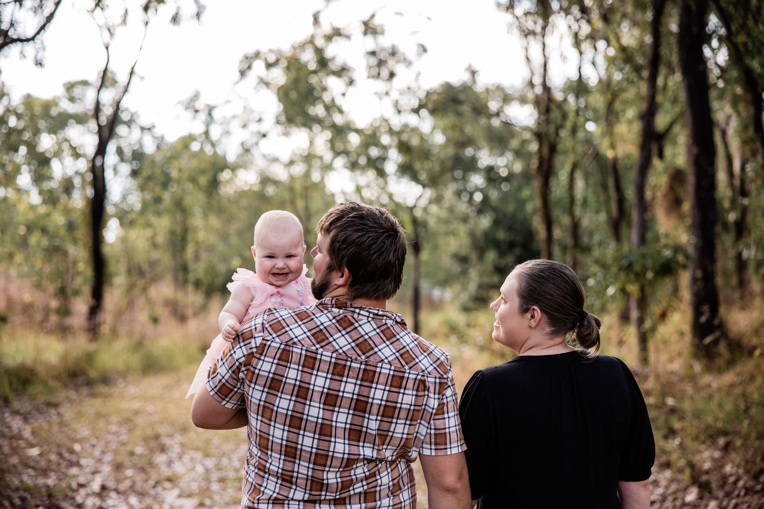 Family walking together on a wooded trail during golden hour.