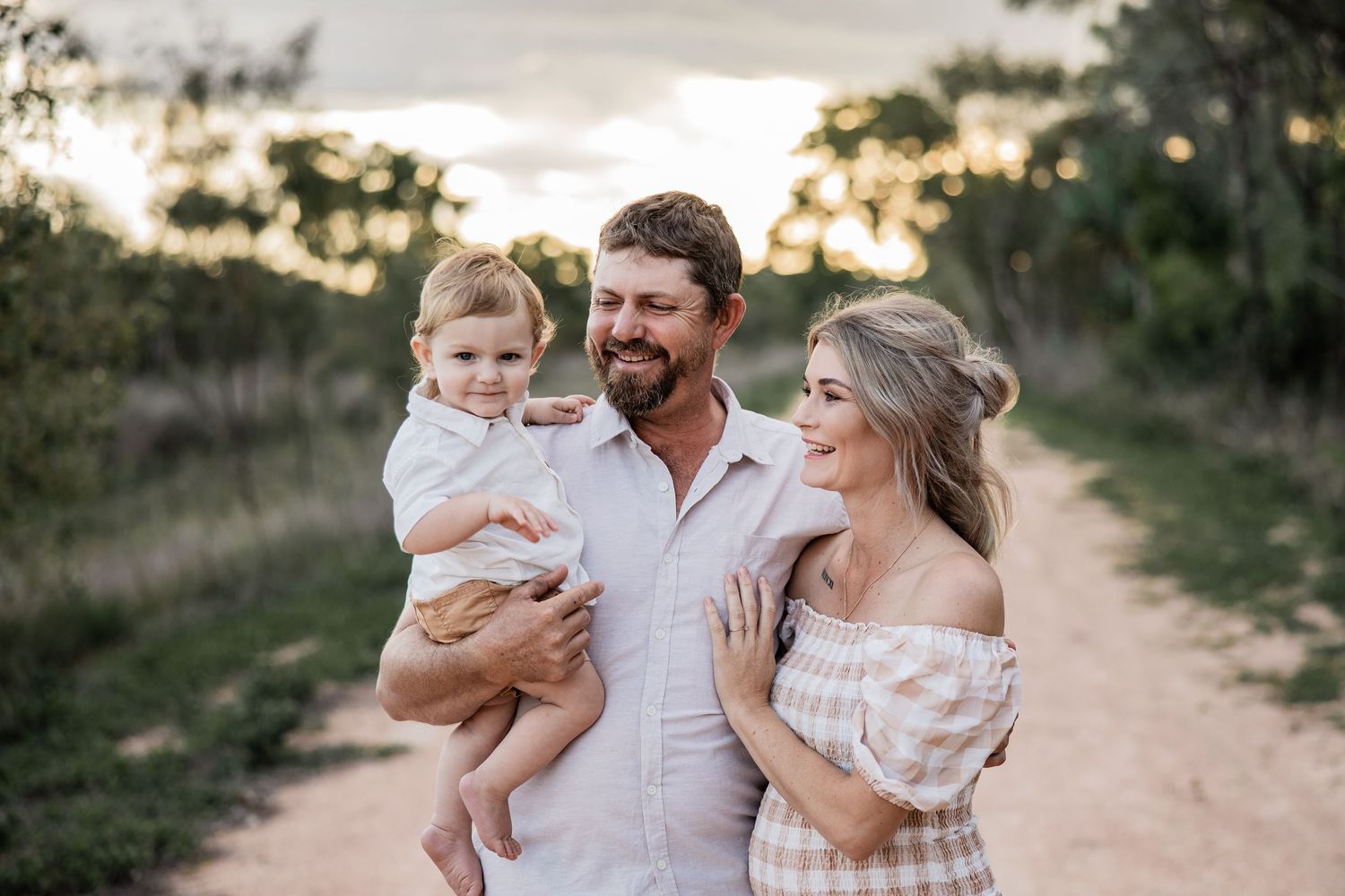 A family shares a tender moment together on a dirt path at sunset.