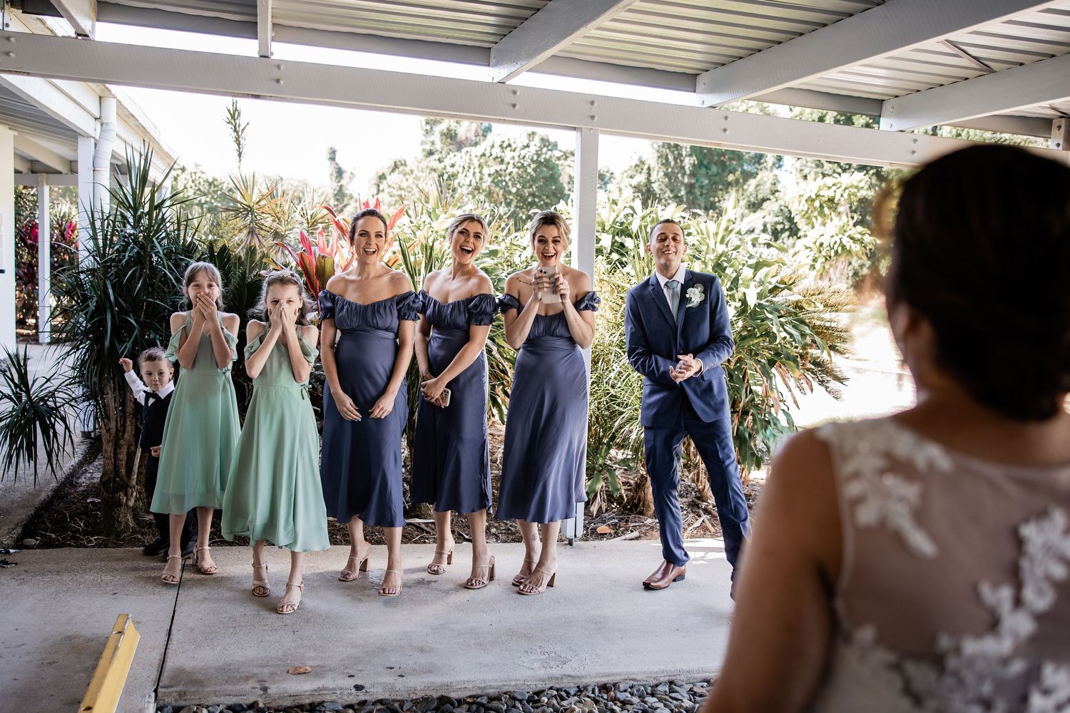 Wedding party in coordinated pastel and navy attire sharing a laughing moment outdoors.