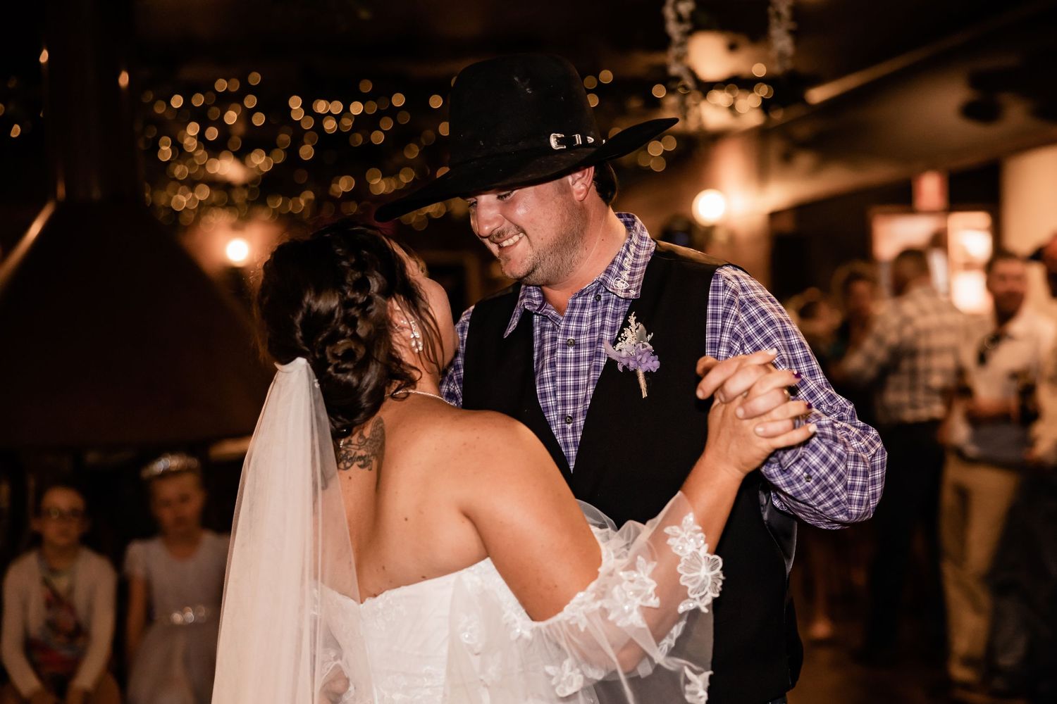 A couple shares an intimate dance moment at their wedding reception under warm lighting.