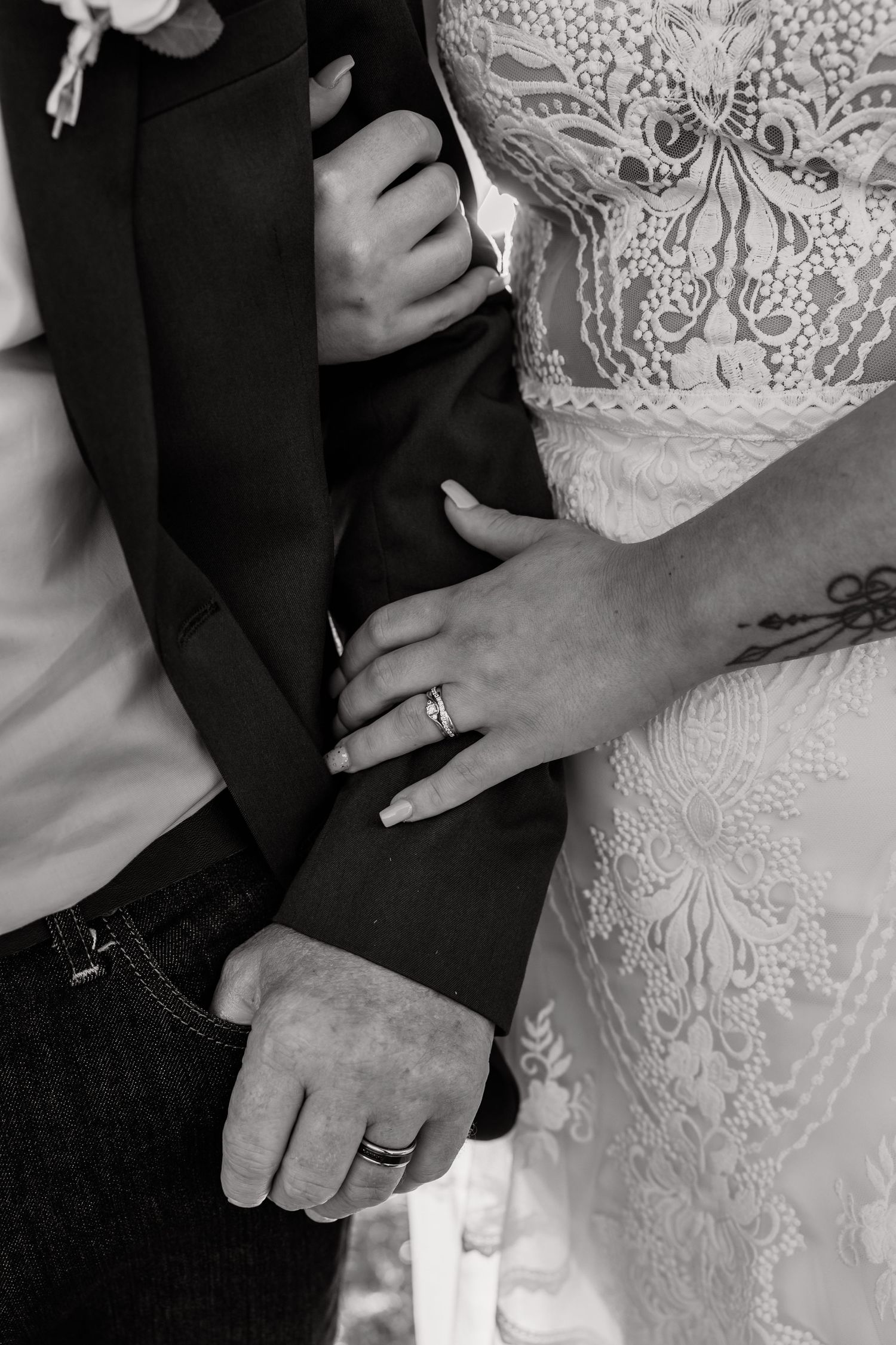 Black and white detail shot of wedding rings and lace dress details.