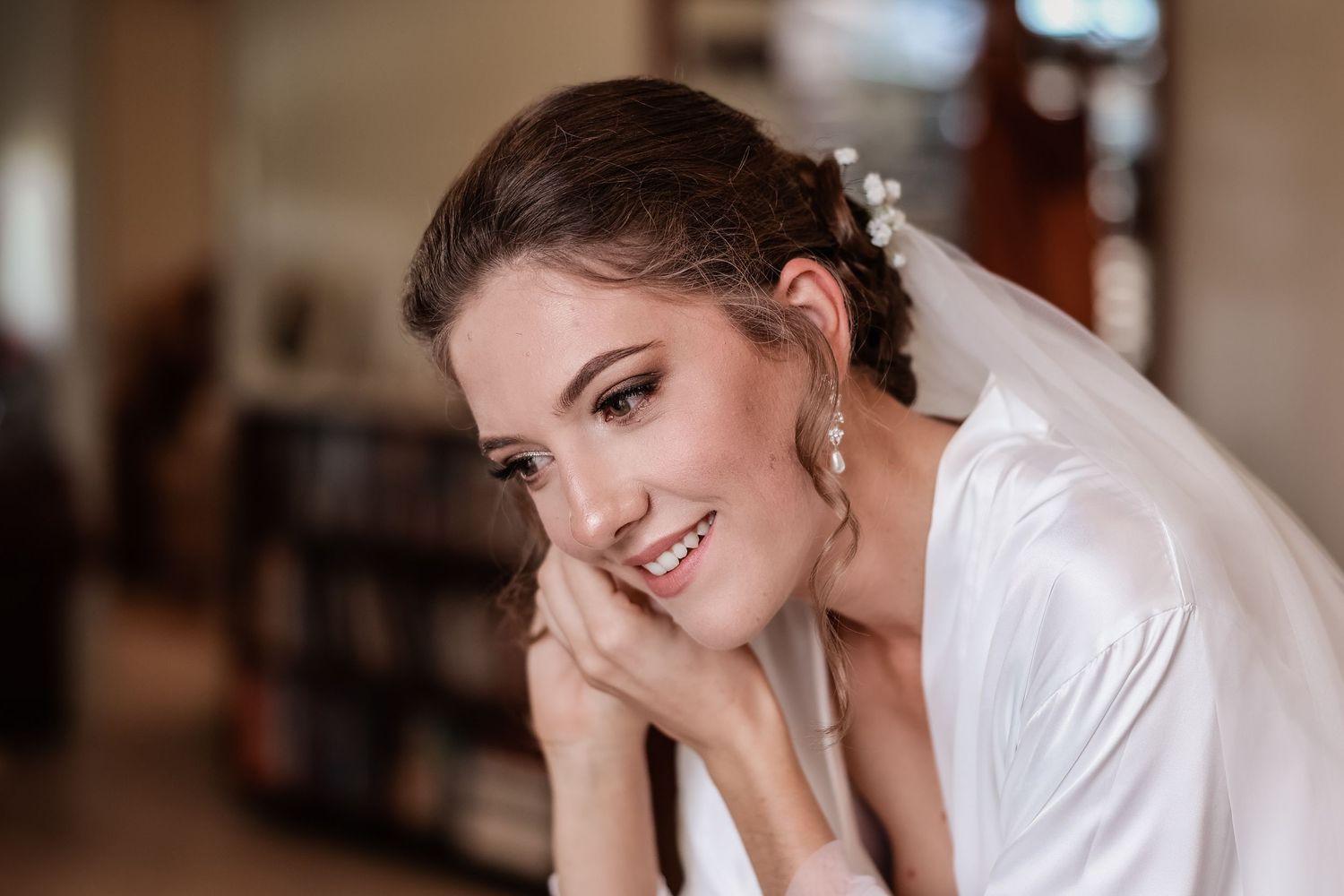 Getting ready photo in soft morning light with bridal robe and delicate jewelry.