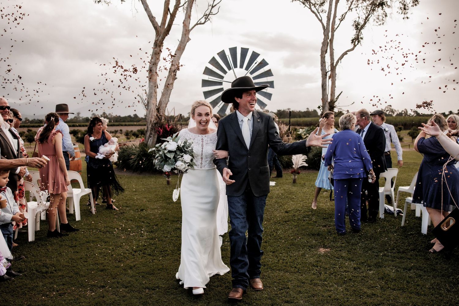 A joyful wedding ceremony outdoors with confetti being thrown as the couple walks down the aisle.