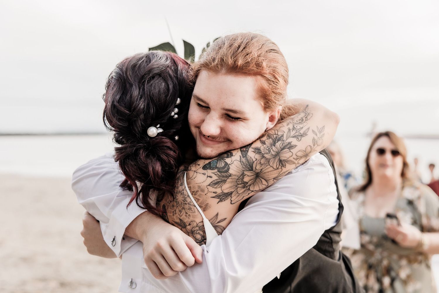 Two people share an emotional embrace during beach wedding celebration.