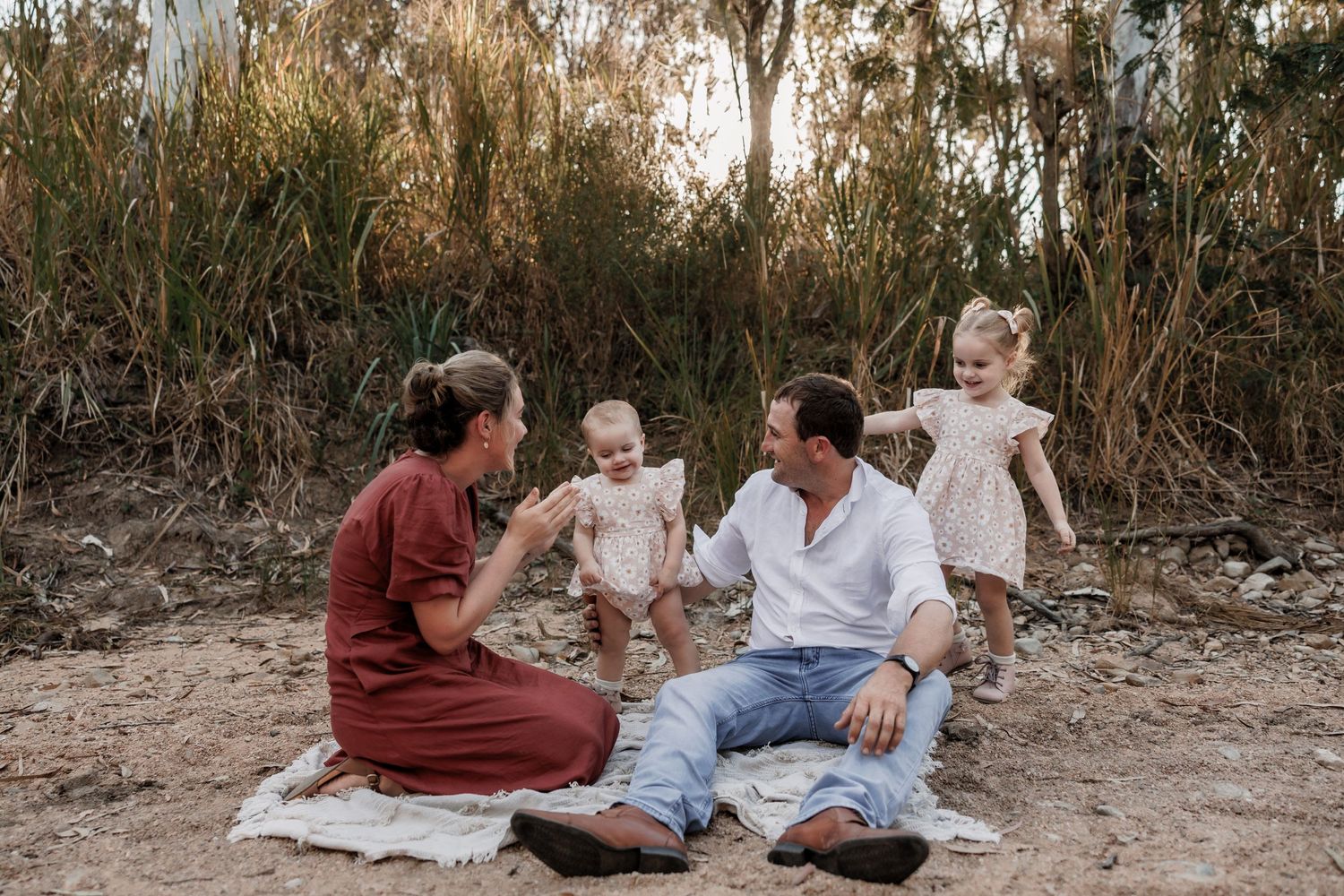 Family enjoying a picnic on a blanket in a rustic outdoor setting.