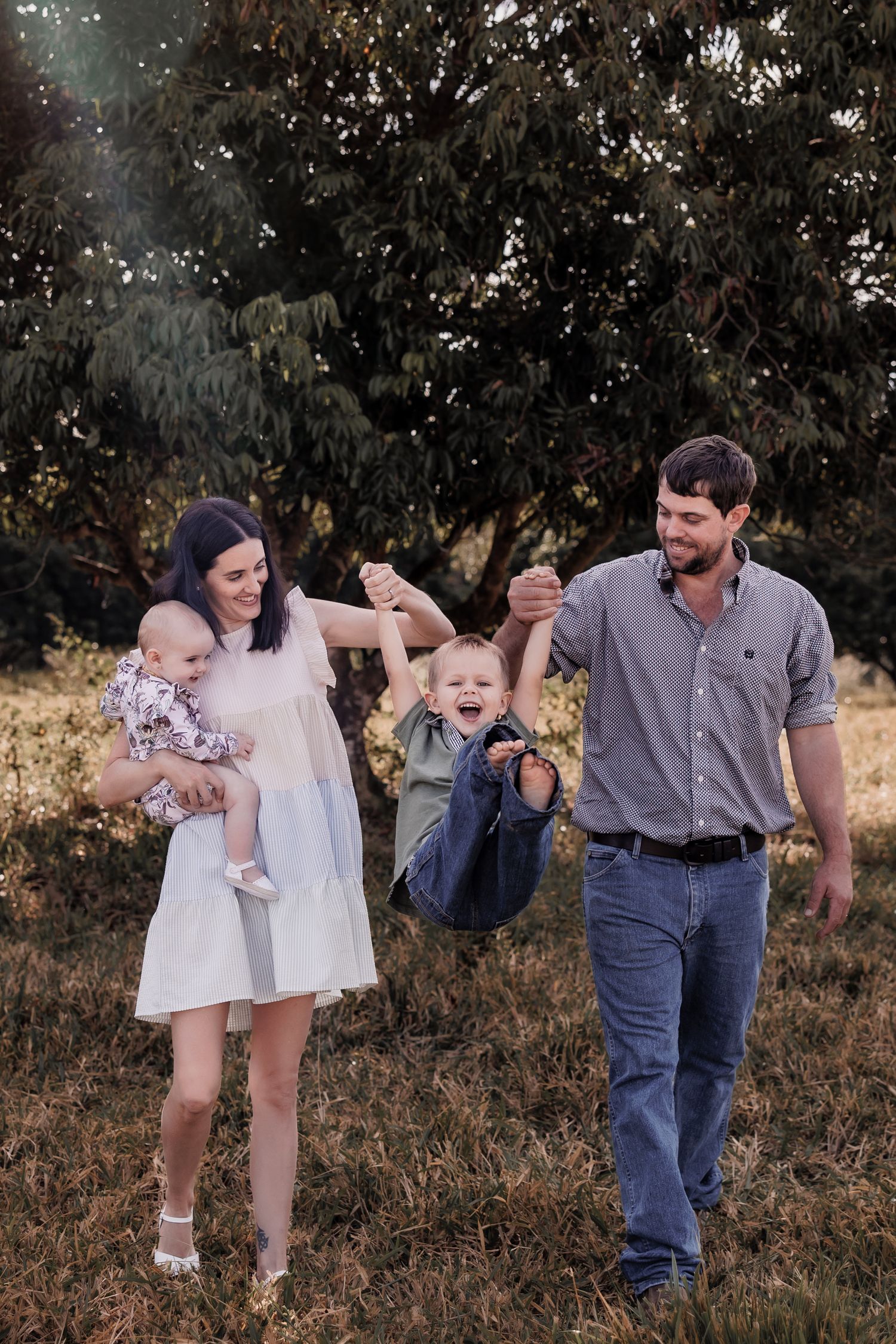 A happy family playing outdoors with their children in a natural setting.