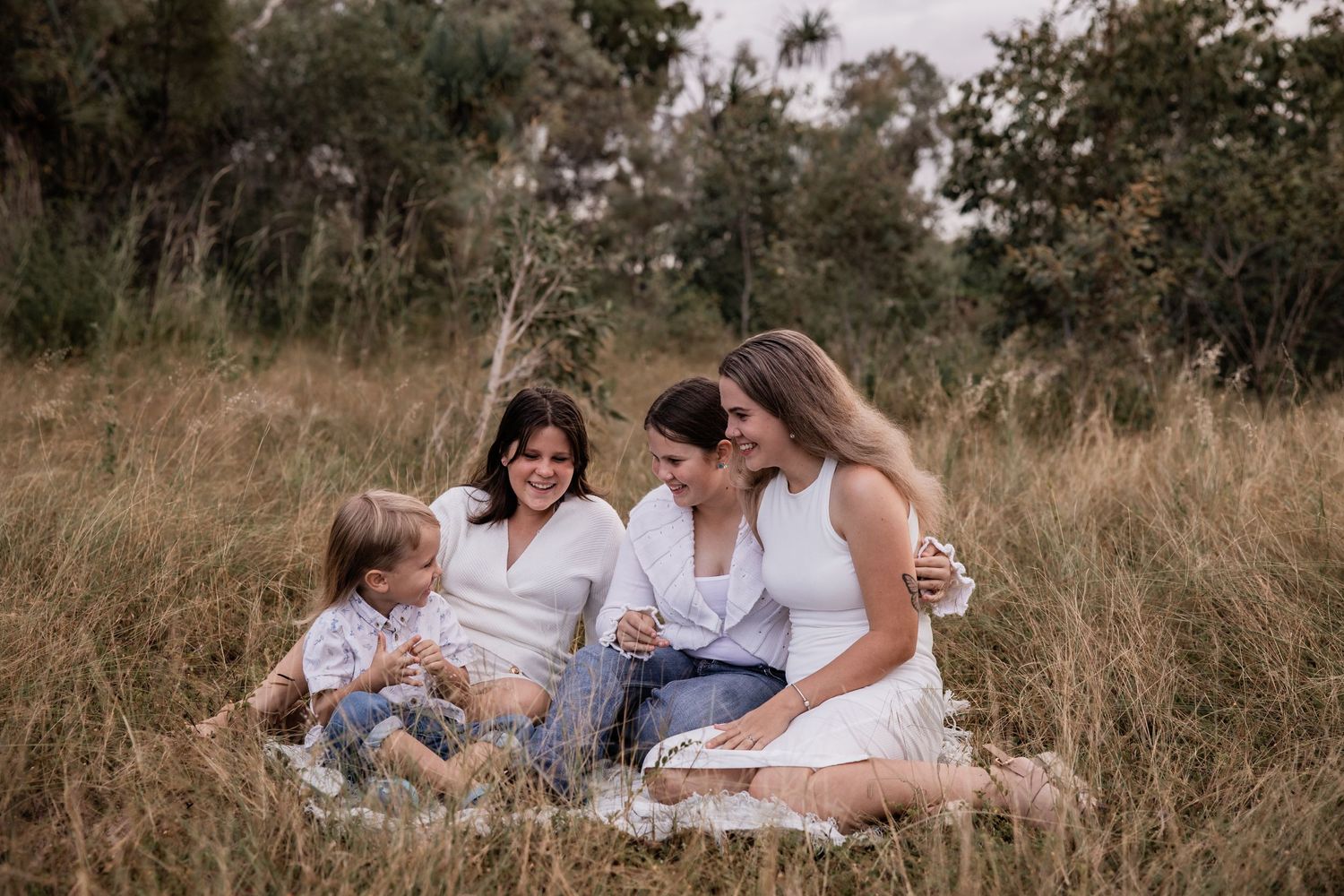 A group sits together in tall grass during an outdoor photo session.