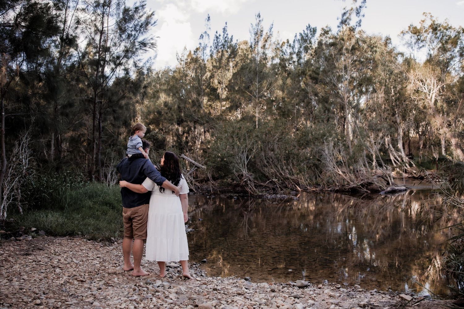Couple standing together by tranquil water's edge in a natural setting.