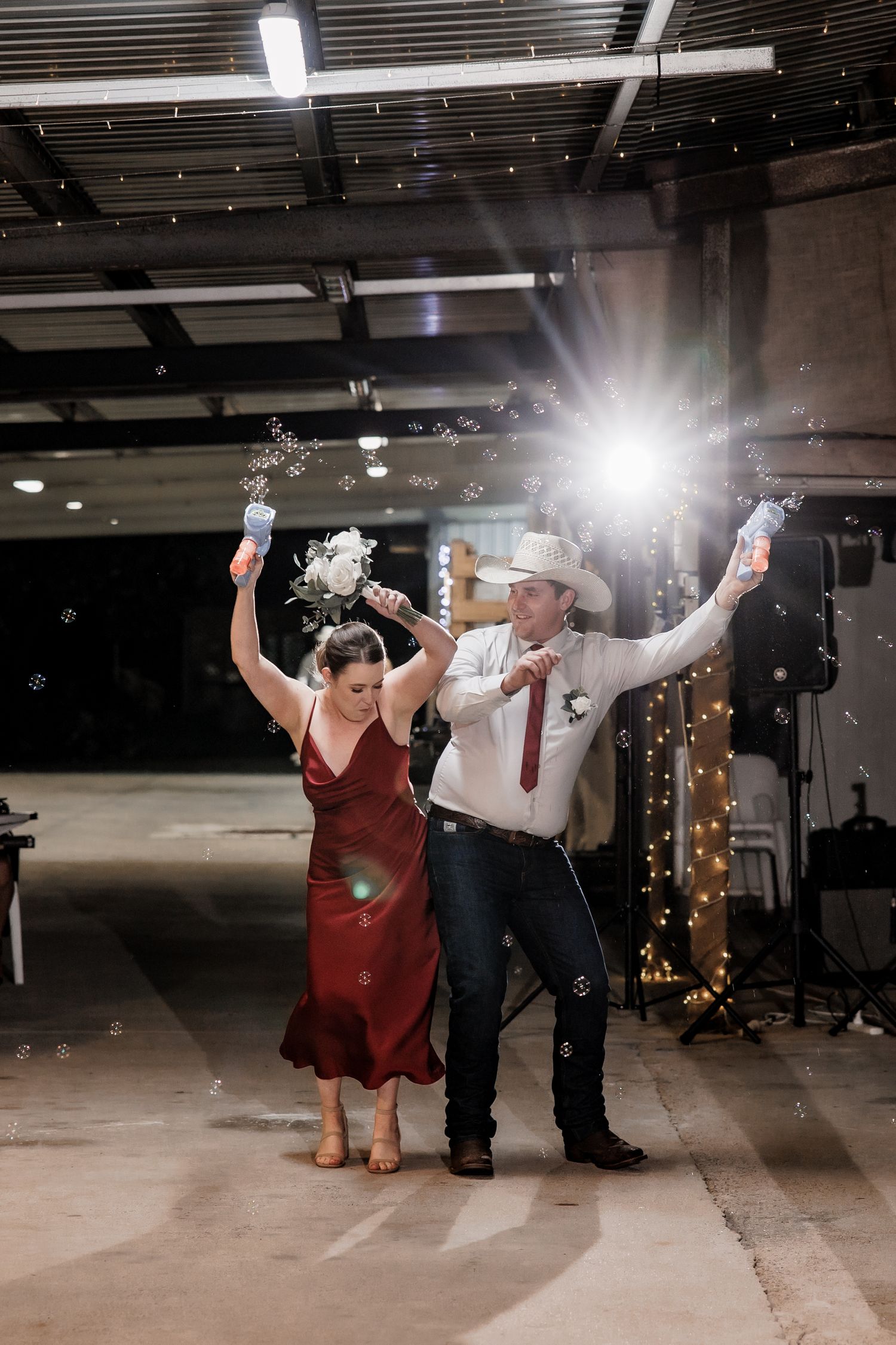 A celebratory dance moment with a couple raising their arms under industrial lighting.
