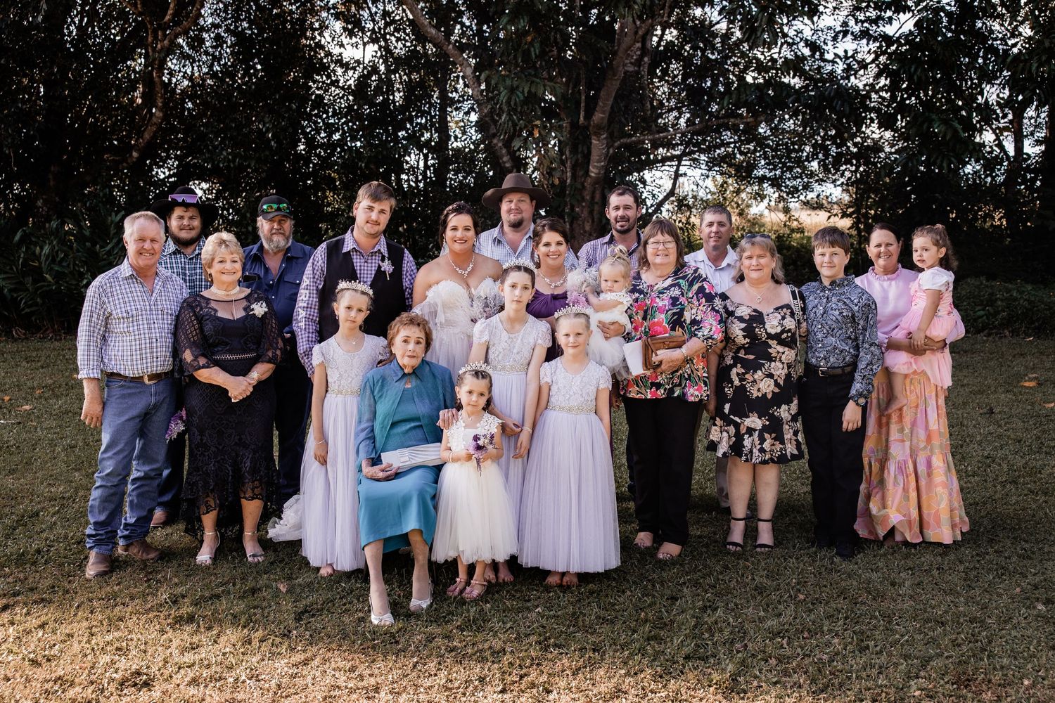 Small wedding party poses outdoors in pastel attire for formal group photo.