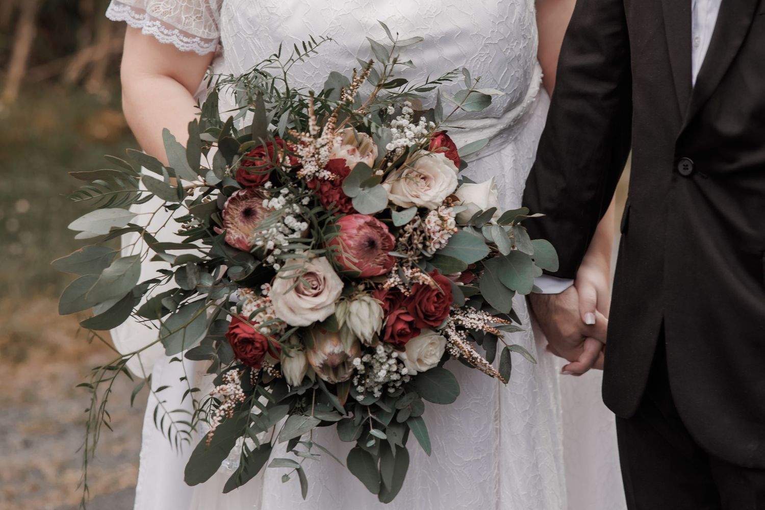 Elegant bridal bouquet featuring roses, eucalyptus, and burgundy blooms.