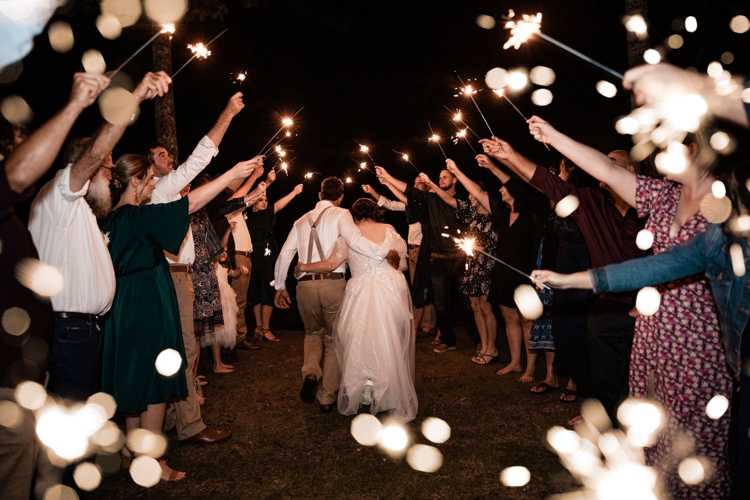 Wedding guests form a sparkler tunnel exit for the bride and groom.