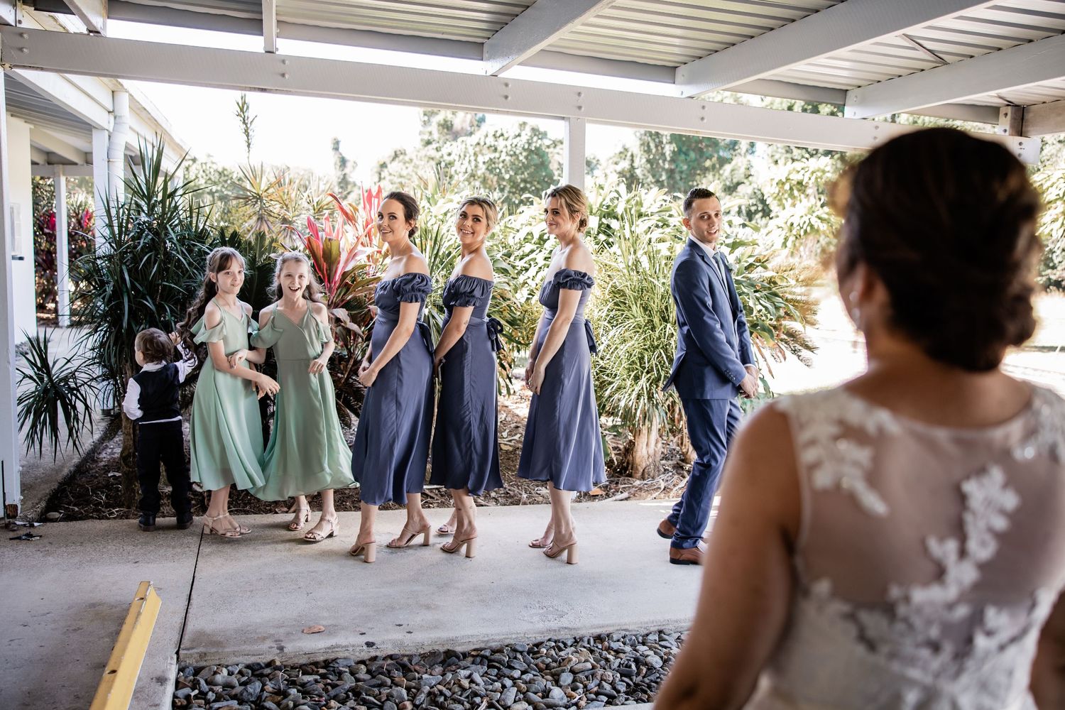 Wedding party in mixed pastel and navy dresses posing under a covered patio.