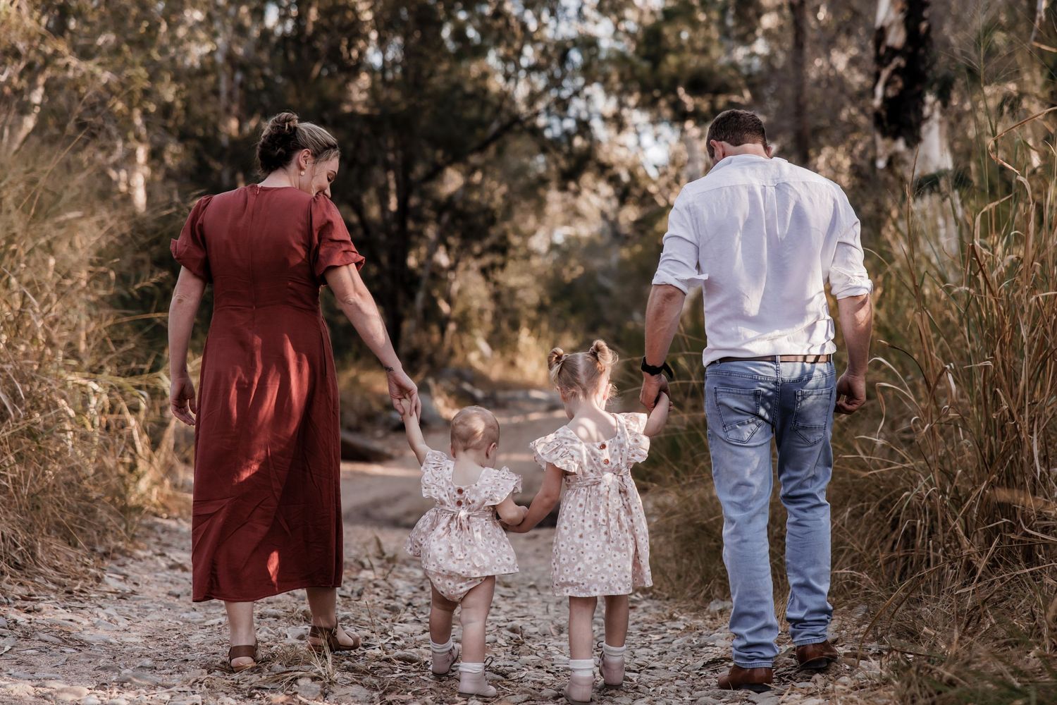 Family walking hand in hand down a nature path at sunset.