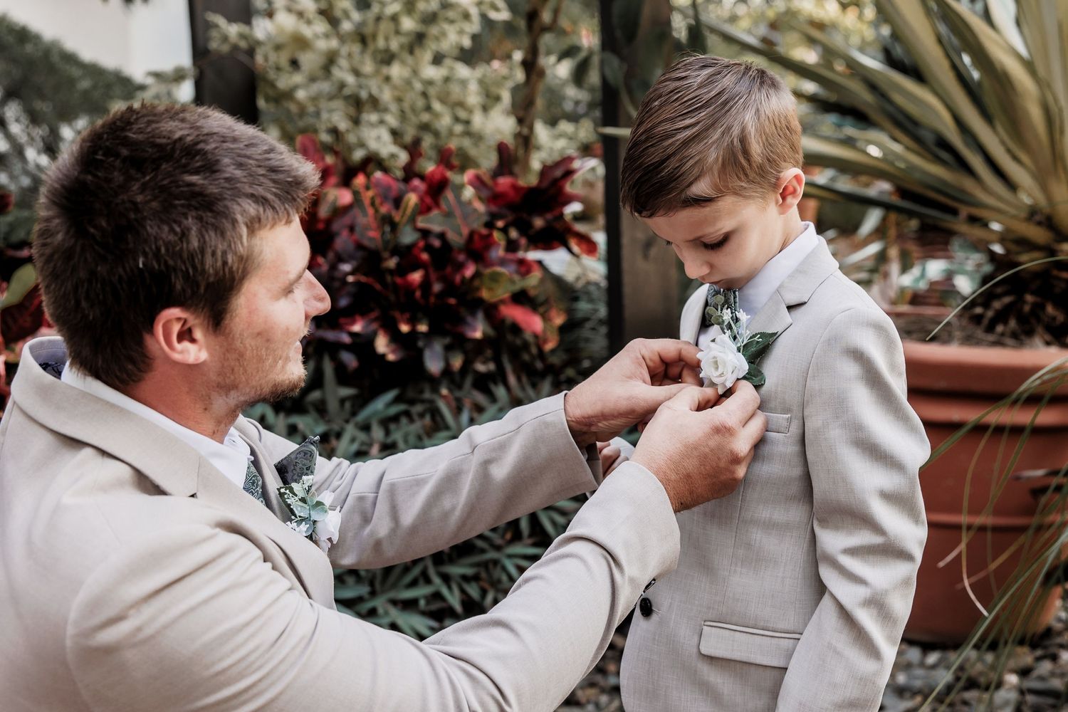 A touching moment as a boutonniere is pinned on a light gray suit.