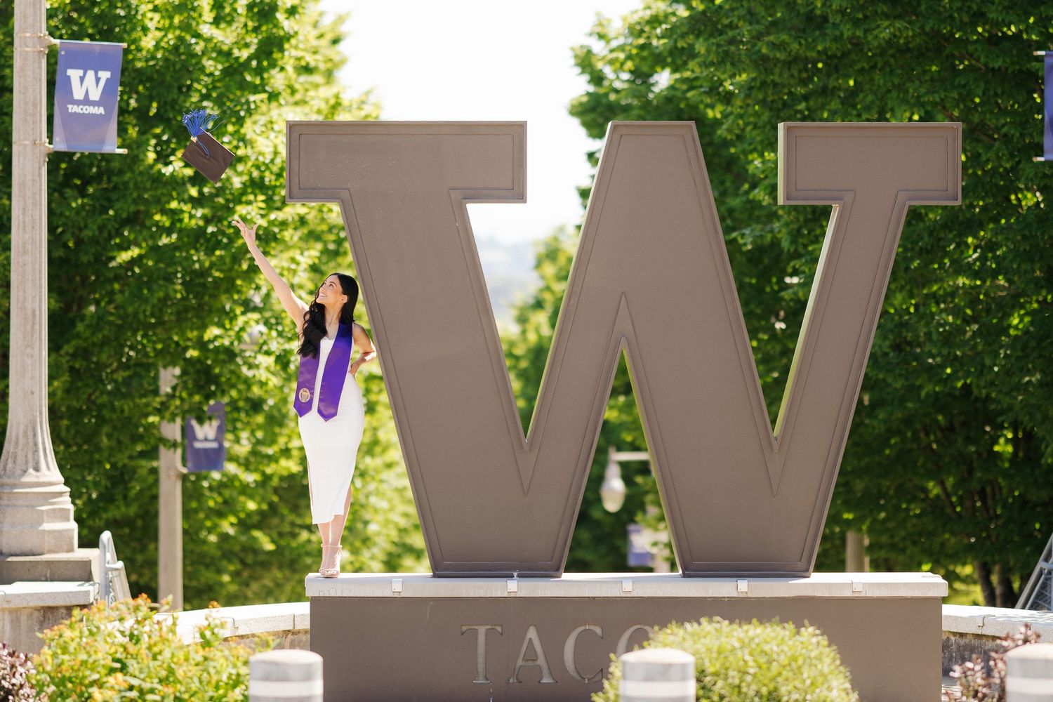 A large stone W letter sign stands on a university campus with trees in the background.