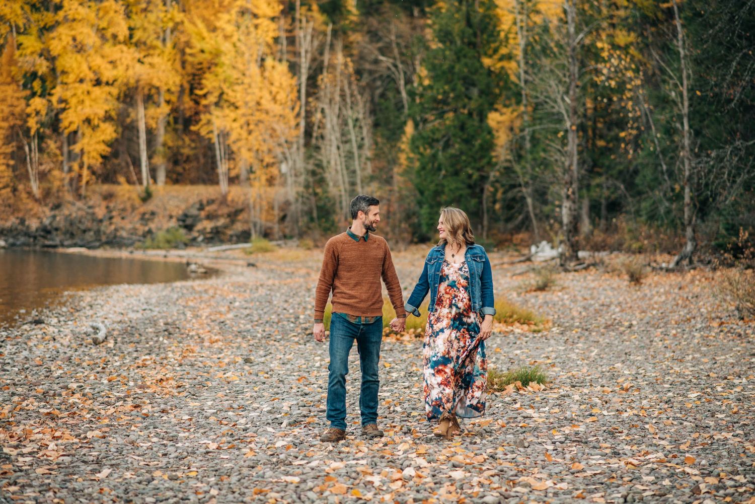 Couple walking on autumn beach with golden foliage and fall colors.