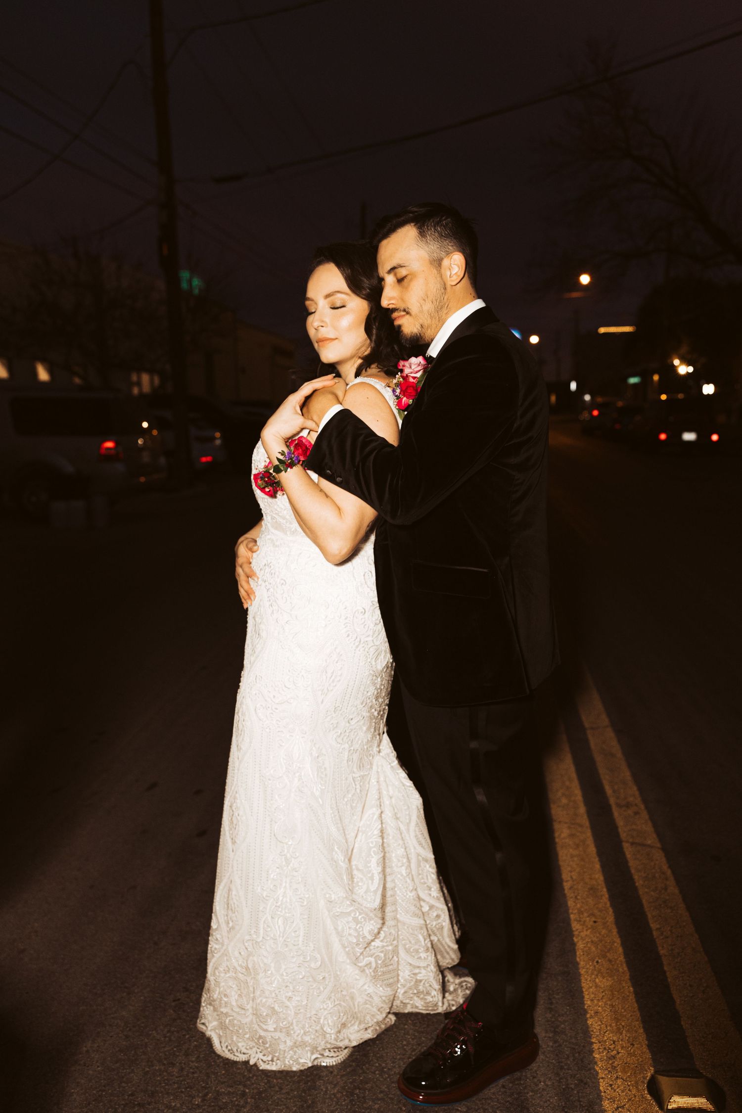 Romantic nighttime portrait of couple dancing in formal attire on street.
