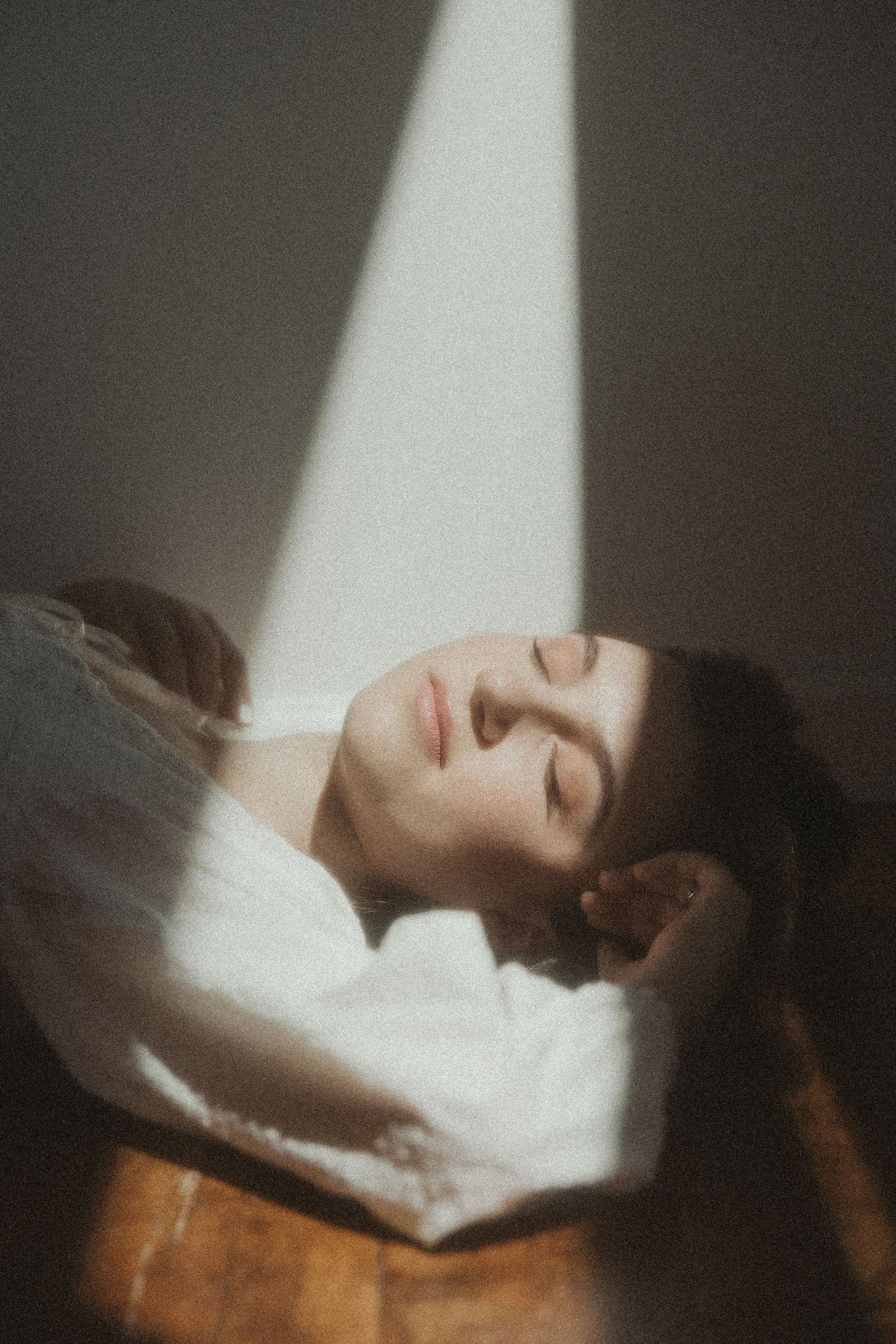 Dramatic portrait in beam of sunlight against dark background.