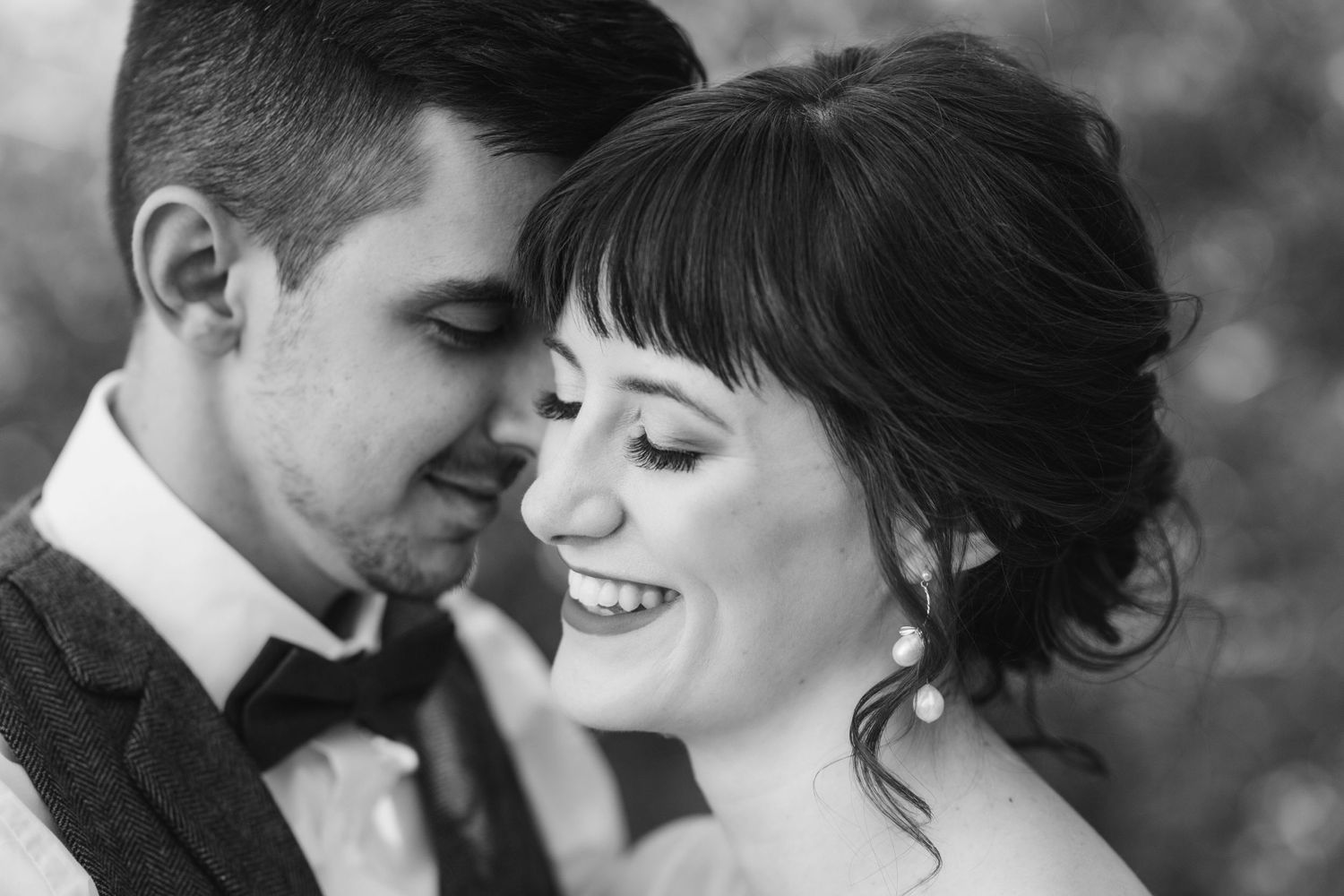 Black and white portrait of smiling bride leaning into groom in tender romantic moment.