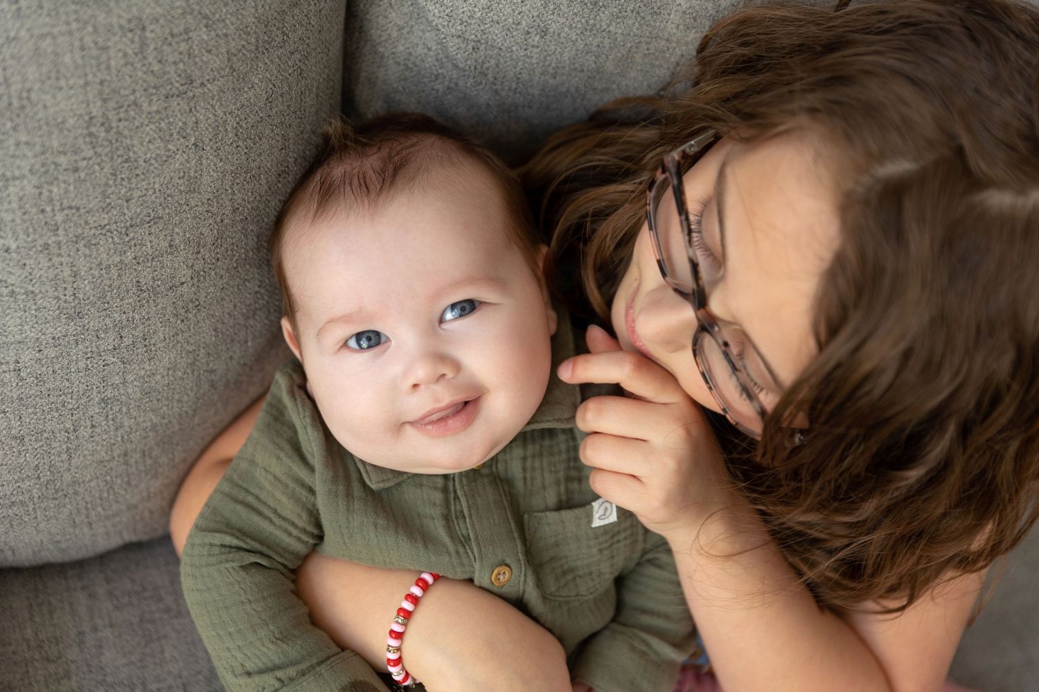 Baby boy smiles as older sister tickles his cheek in Worthington Ohio