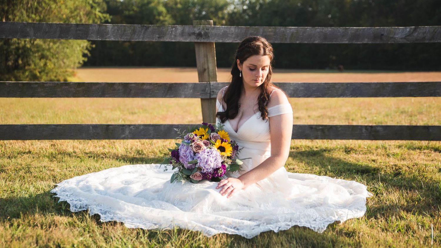 A posed photo of a bride in her wedding dress with her bouquet in her lap.