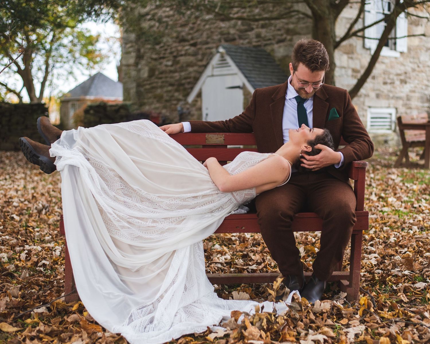 A newlywed couple lounging together on a park bench.